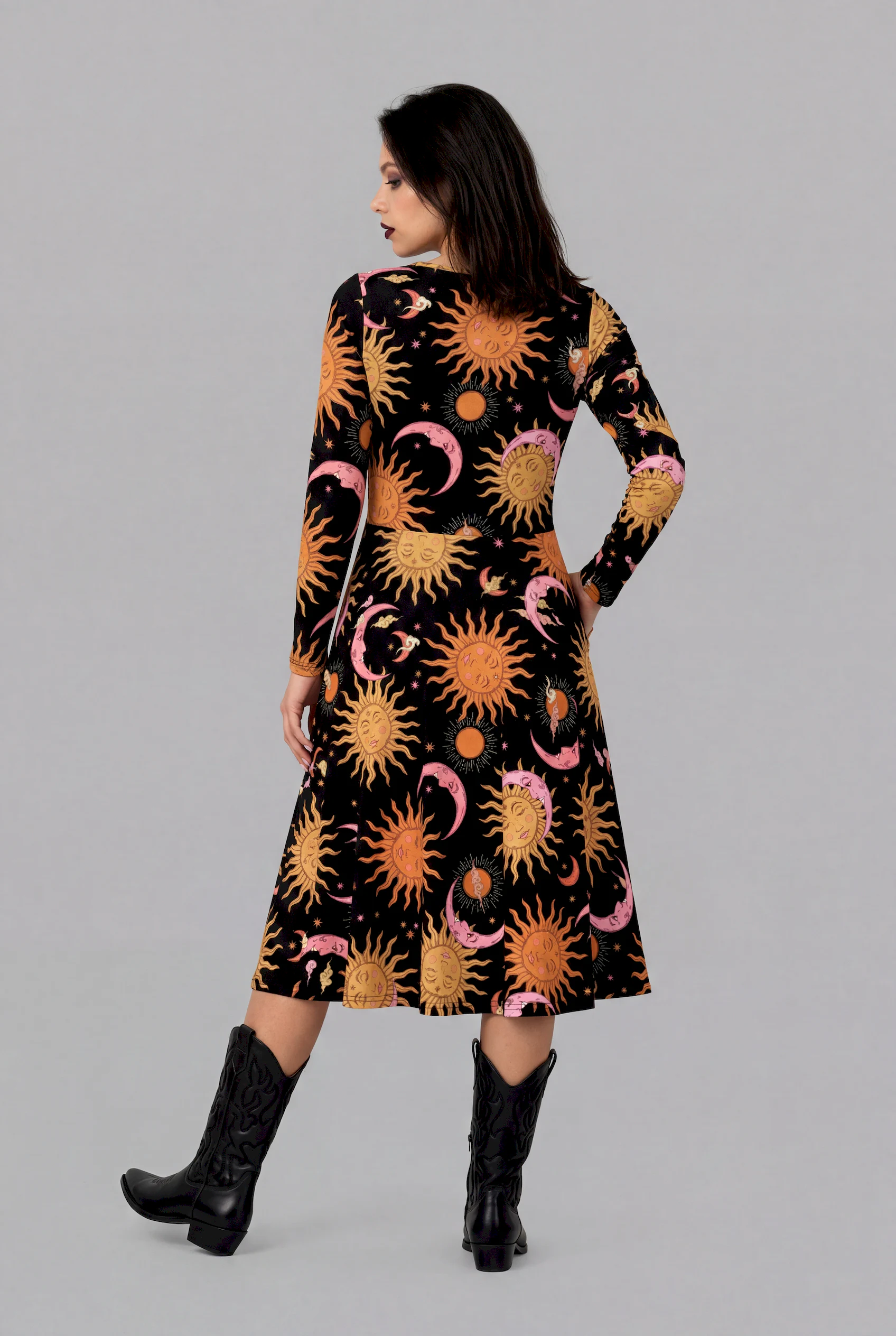 Rear side view of Celestial Dreams print long sleeve midi dress with celestial print and black cowboy boots